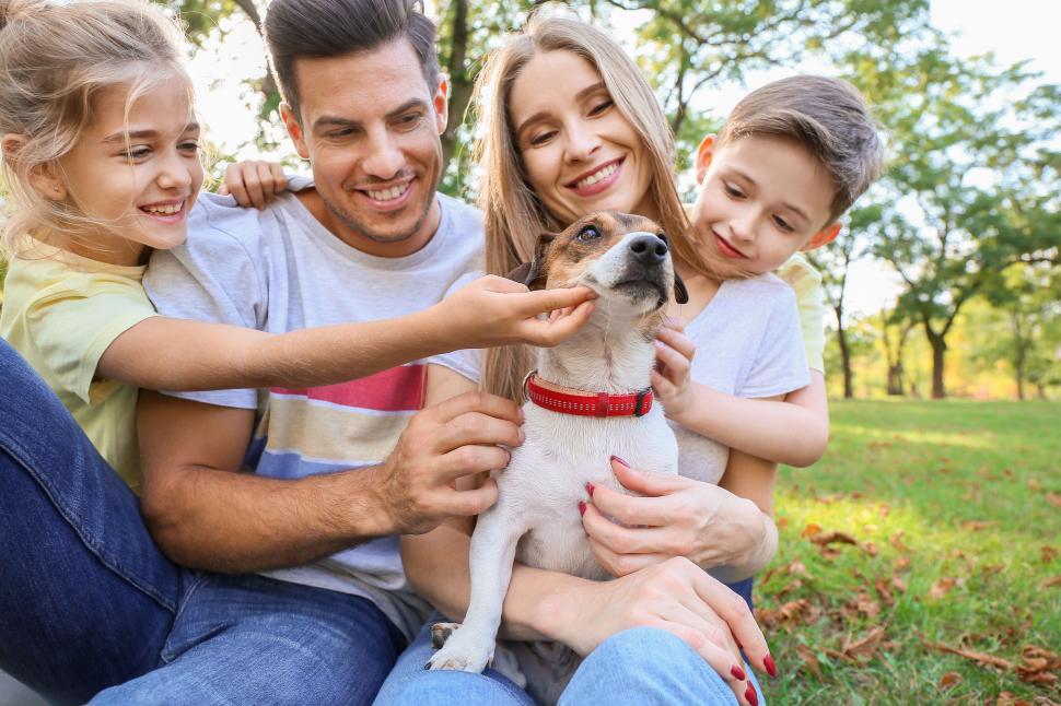 Free Image of Joyful family holding pet dog smiling at camera 