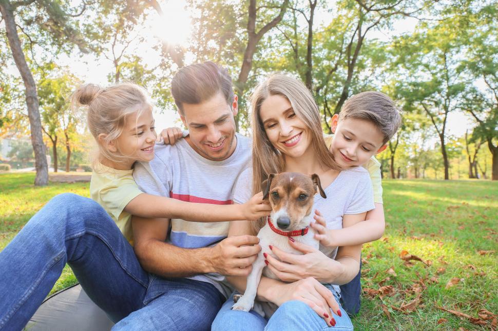 Free Image of Family and dog sitting on grass in sunny park 