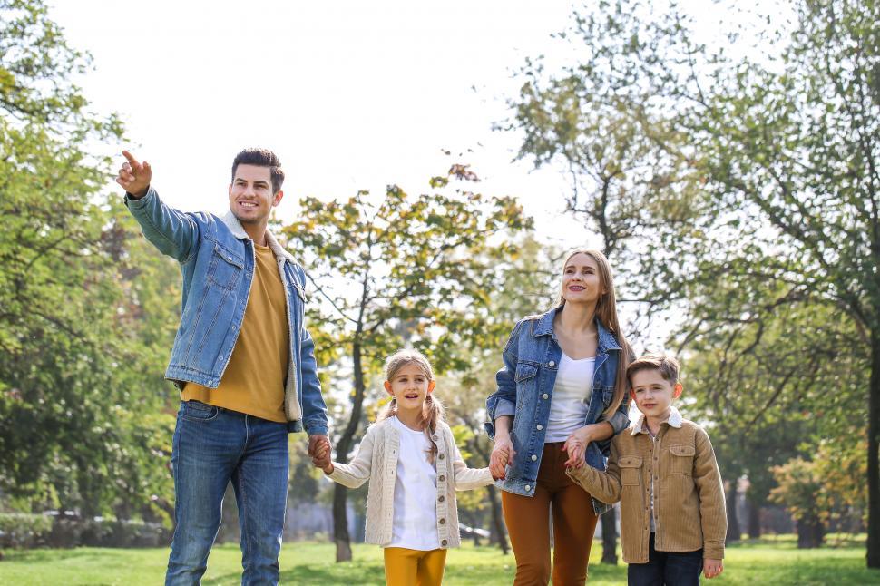 Free Image of Family walking in park pointing ahead smiling 