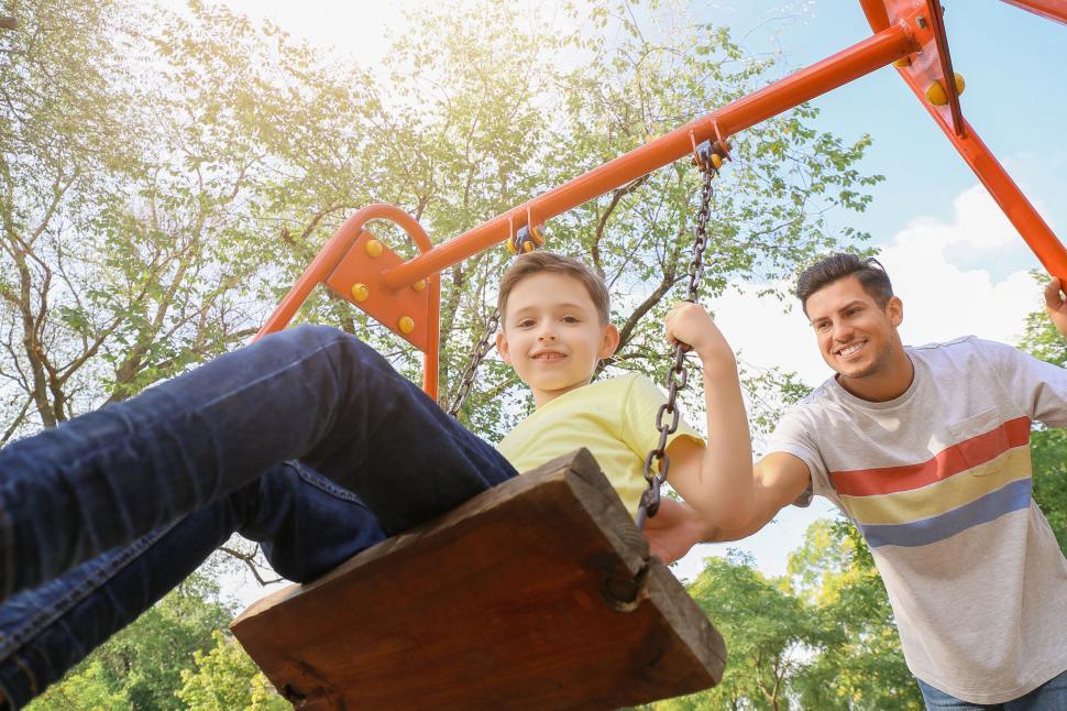 Free Image of Boy swinging with father s assistance at park 