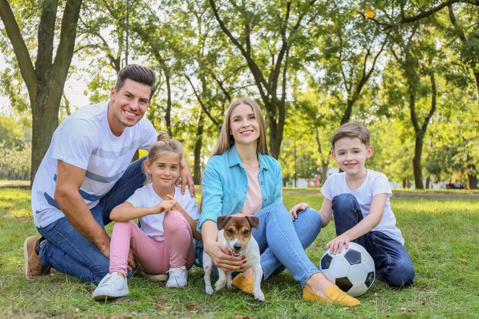 Free Image of Family and dog sitting on grass in park 