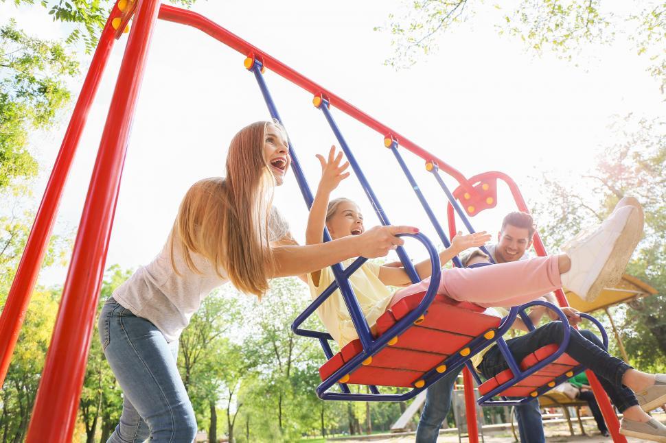 Free Image of Family playing on a bright playground swing 