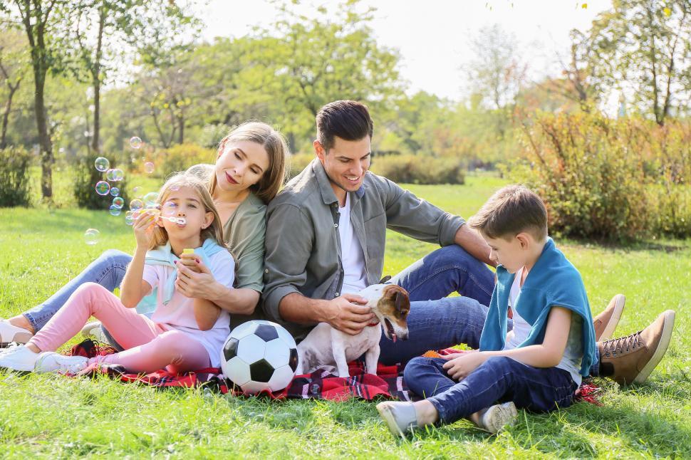 Free Image of Family sitting with dog and blowing bubbles 