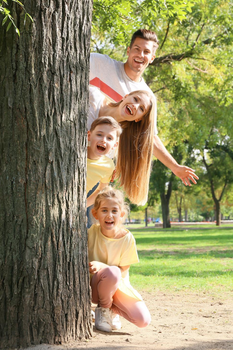 Free Image of Family playing behind a tree in park 
