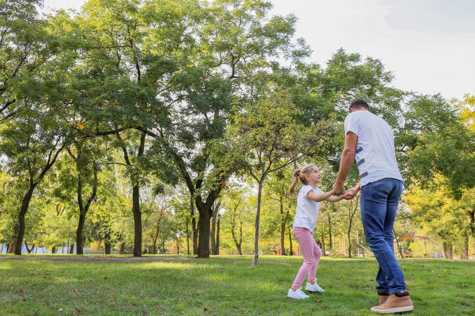 Free Image of Dad spinning daughter around in park 