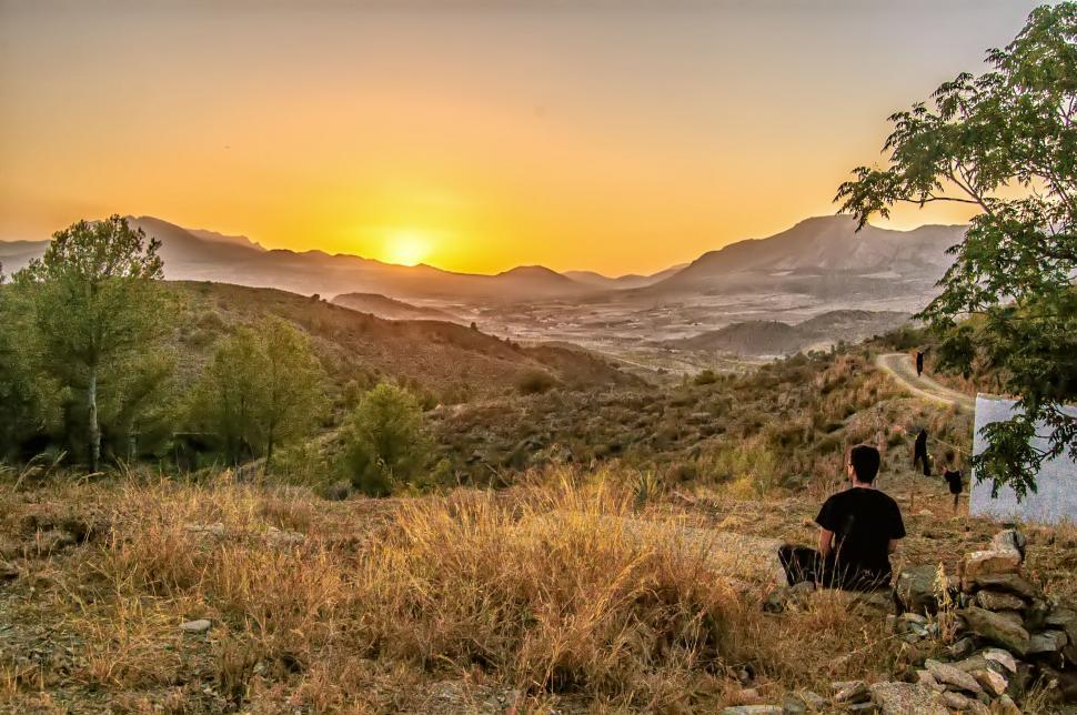 Free Image of Man watching sunset in serene landscape 