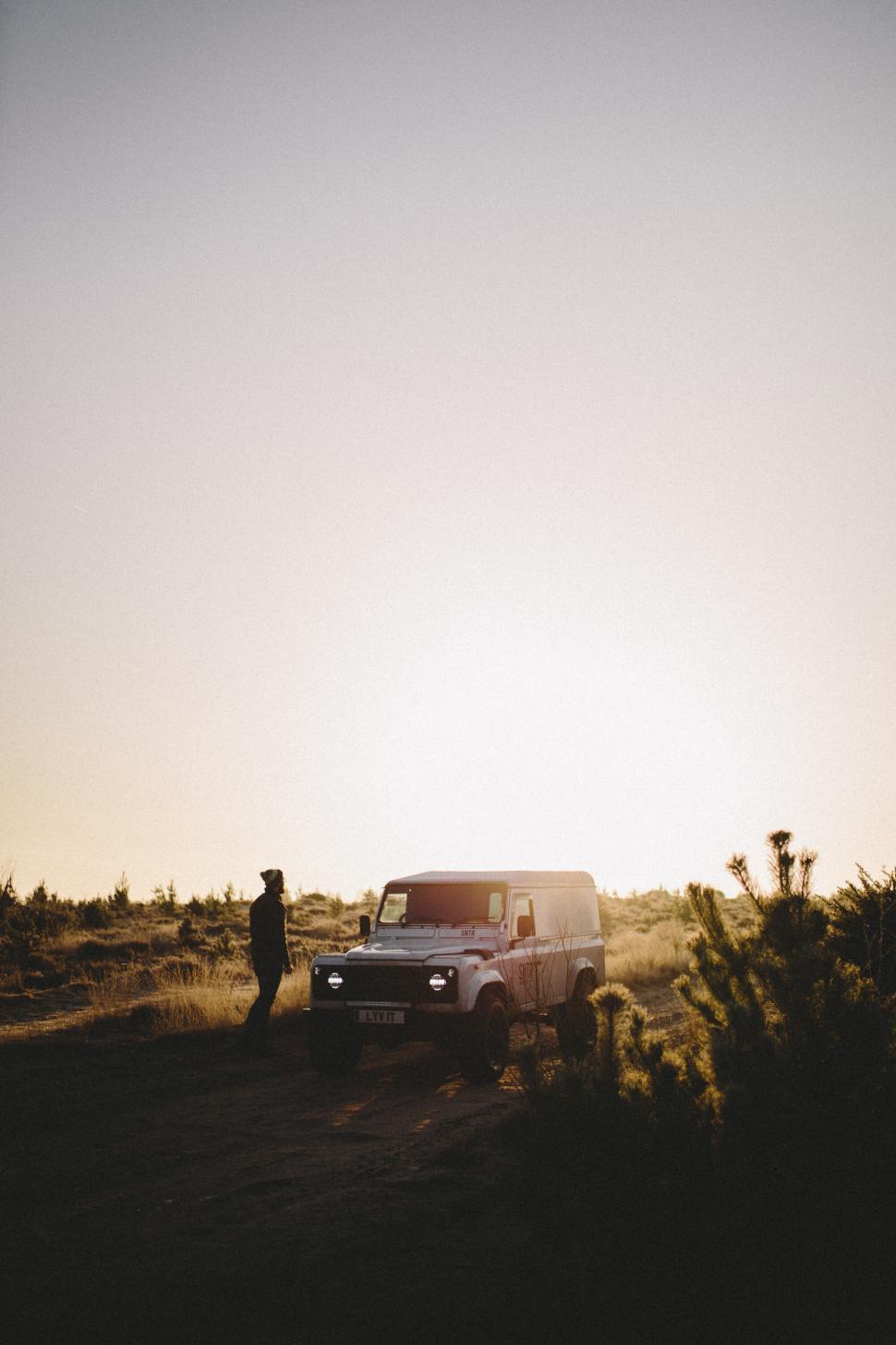 Free Image of Silhouette of a man beside a van at sunset 