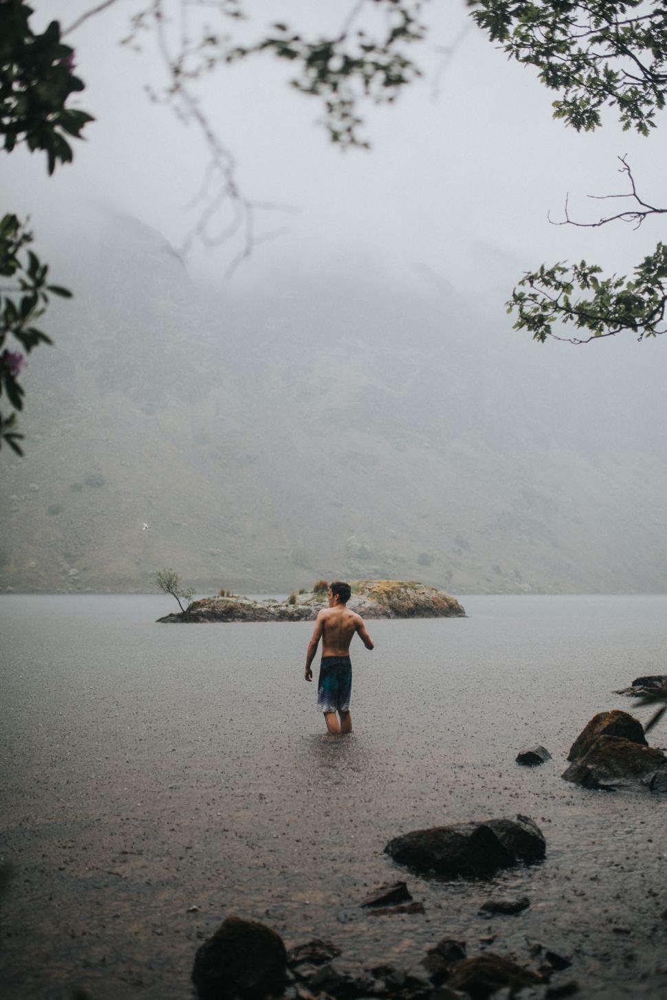 Free Image of Man wading in misty mountain lake 