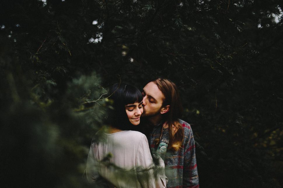 Free Image of Couple sharing a kiss amidst forest trees 