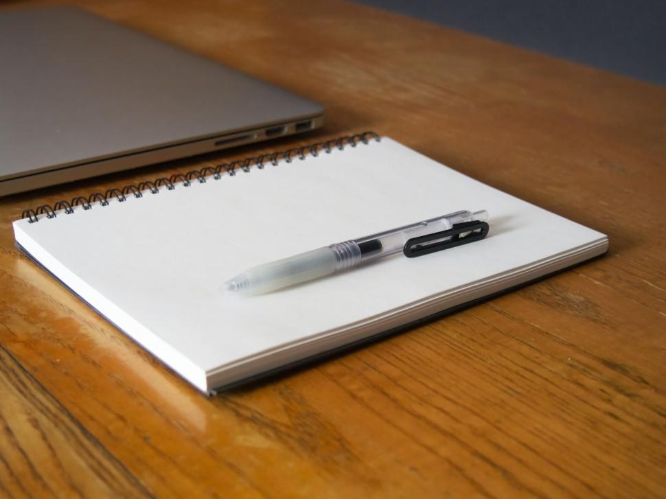 Free Image of Notebook with pen on wooden table near laptop 