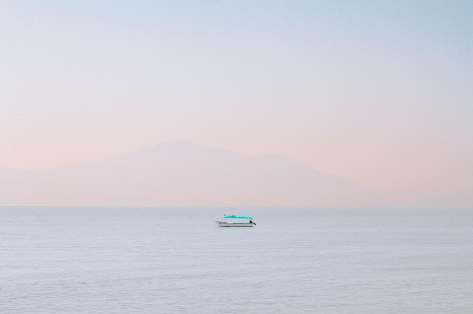 Free Image of Boat sailing on calm sea at pink sunset 