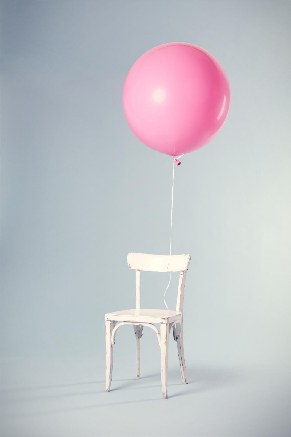 Free Image of Pink balloon tied to a white chair 