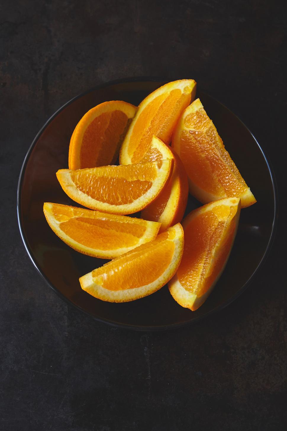 Free Image of Fresh orange slices on a dark plate 