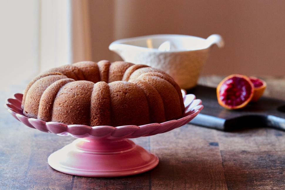 Free Image of Bundt cake on a pink cake stand with pomegranate 