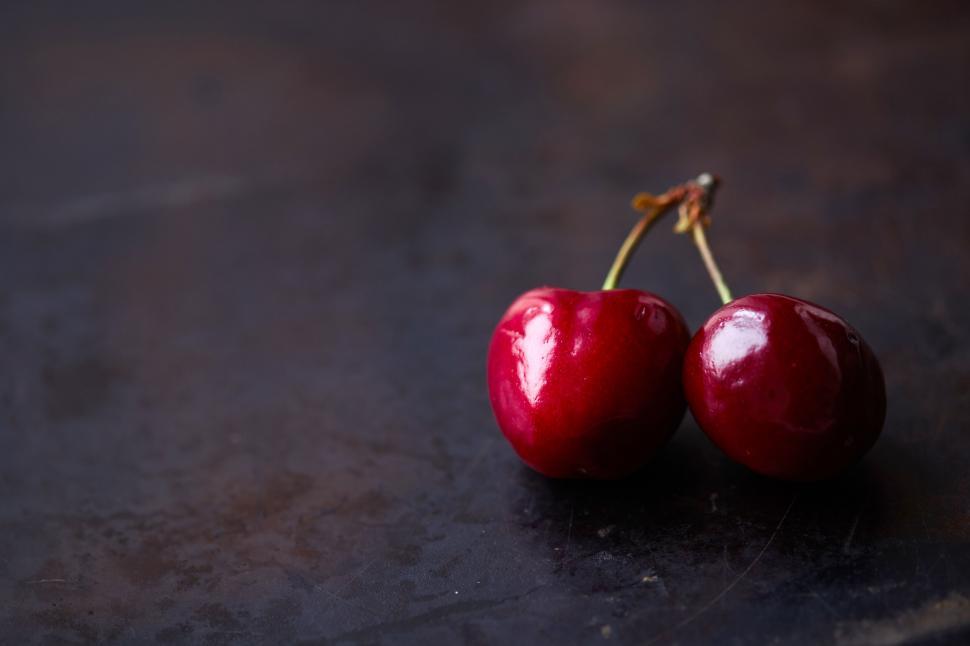 Free Image of Pair of shiny fresh cherries on dark surface 