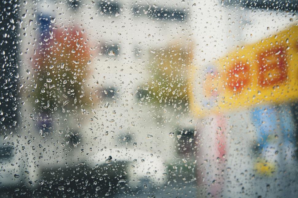 Free Image of Raindrops on a window with blurry city background 