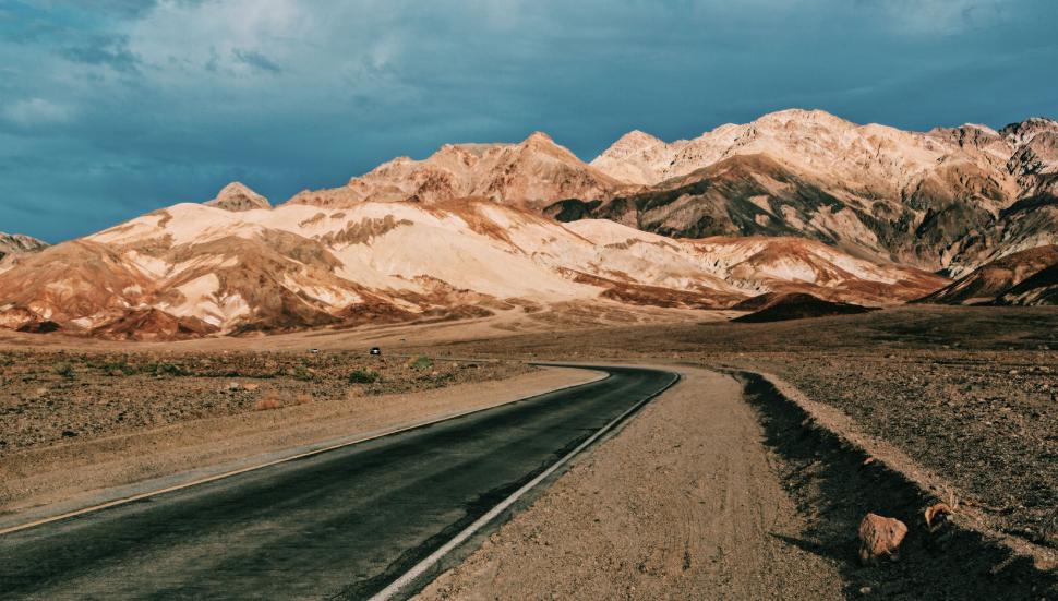 Free Image of Desolate road winding through colorful hills 