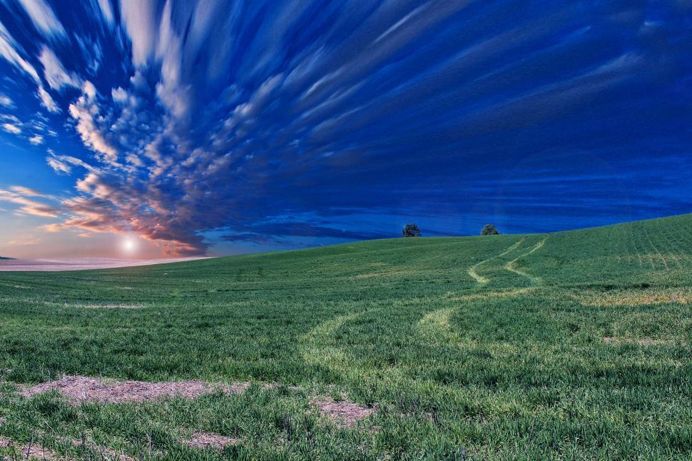 Free Image of Sunrise over lush green hill with dynamic sky 