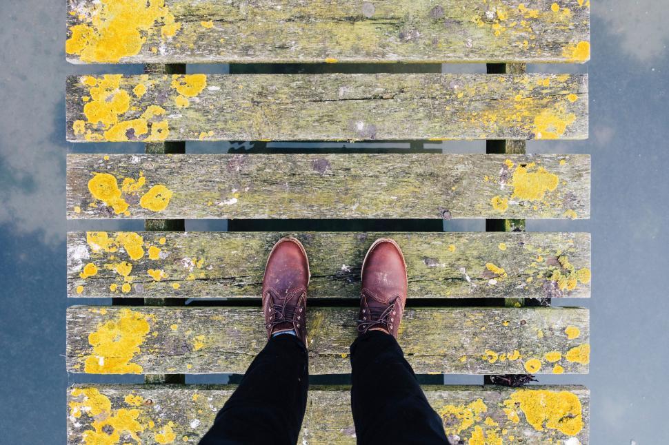 Free Image of Person standing on old wooden pier with moss 