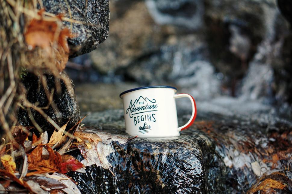 Free Image of Enamel mug with adventure quote by stream 