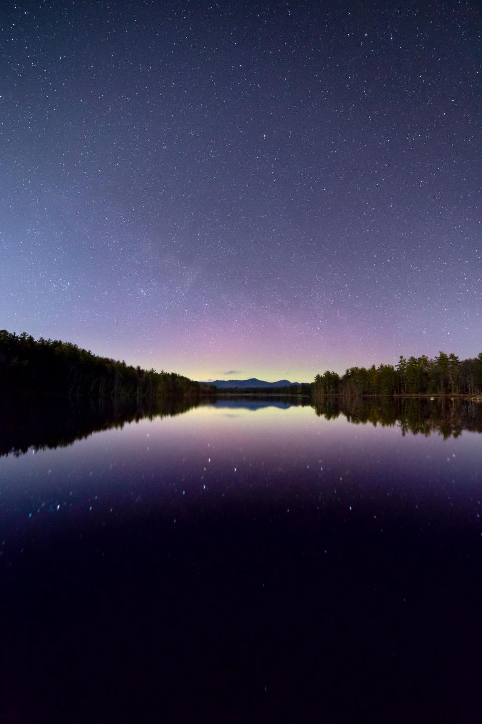 Free Image of Starry night sky reflected in a tranquil lake 