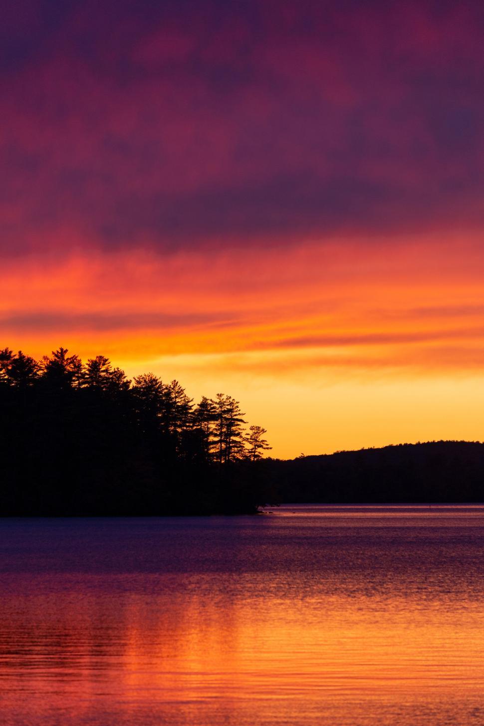 Free Image of Vibrant sunset over a calm forest lake 