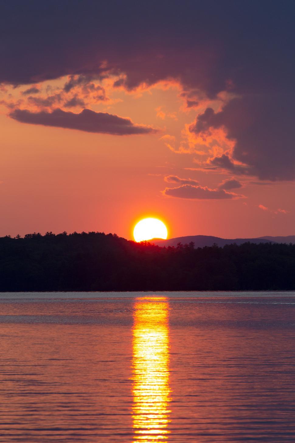 Free Image of Sunset over lake with silhouetted forest 