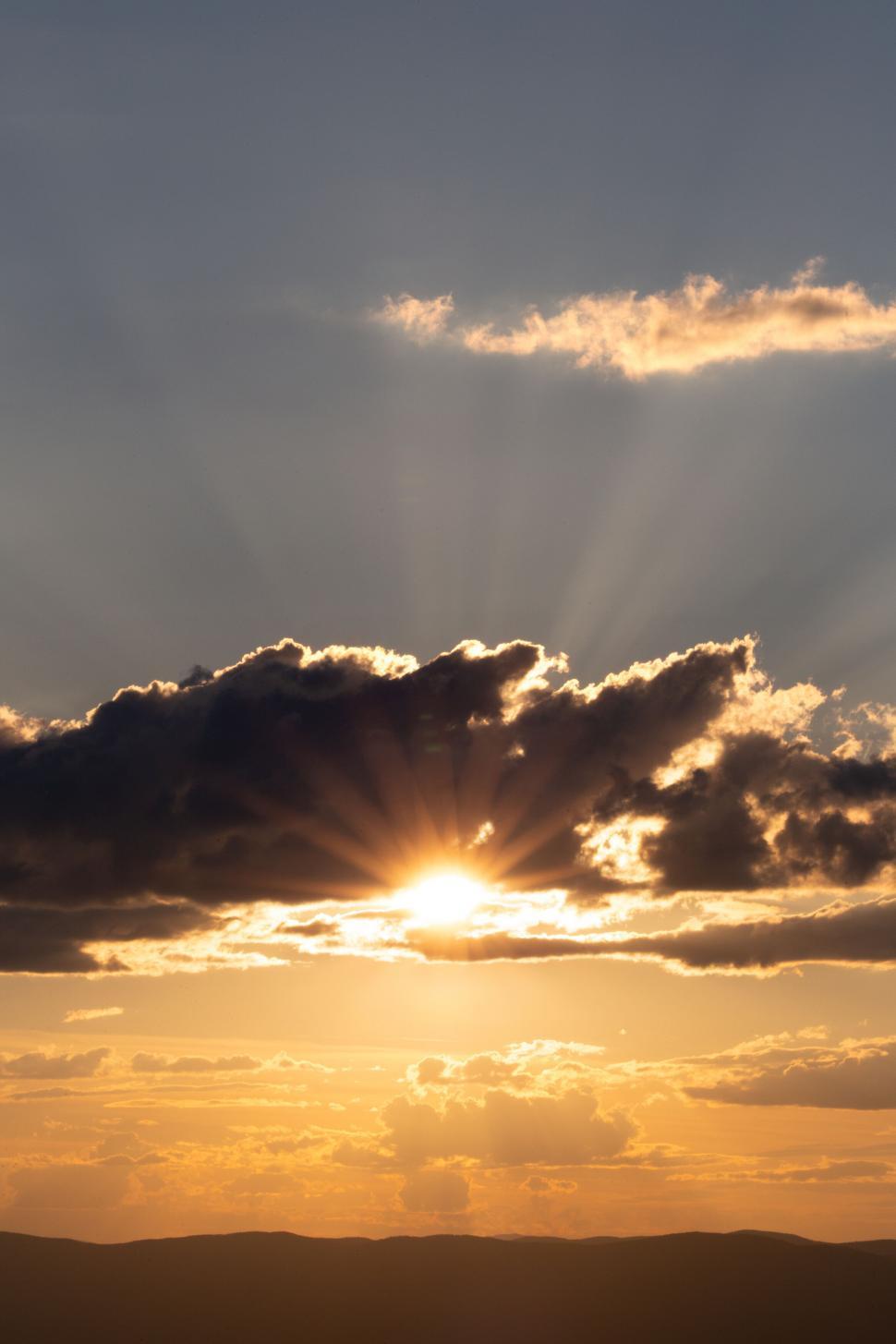 Free Image of Sunset with sunbeams piercing clouds 