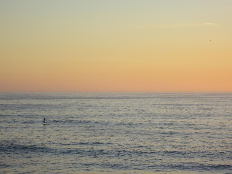 Free Image of Paddleboarder in the ocean at sunset 