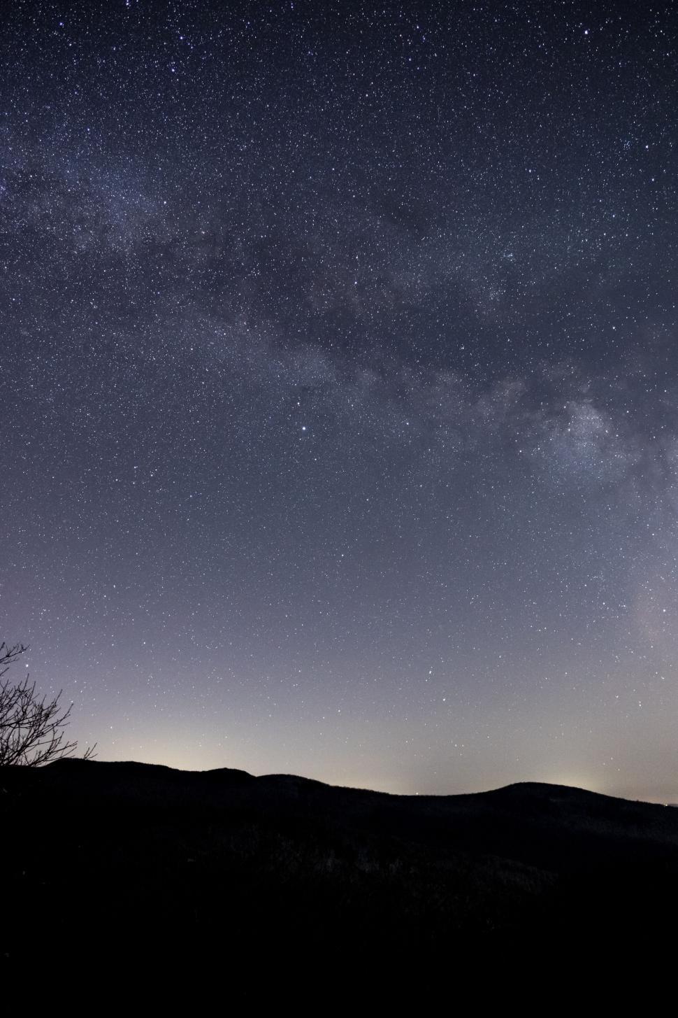 Free Image of Stars twinkling in the night sky over mountains 