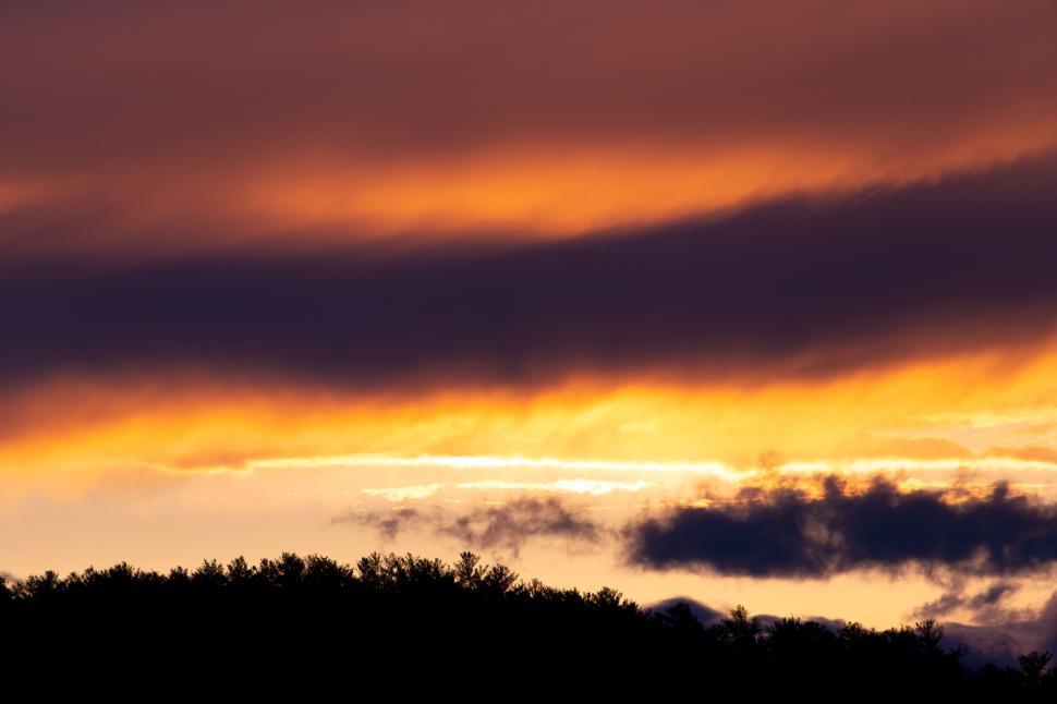 Free Image of Dramatic sunset with clouds over silhouette hills 