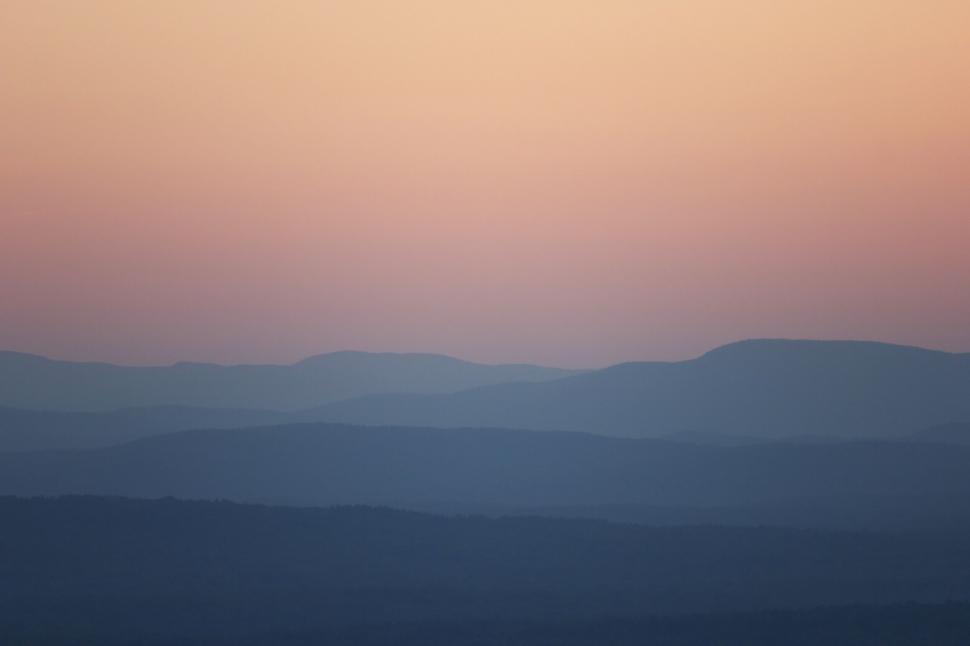 Free Image of Pastel sunset over layered mountain silhouettes 
