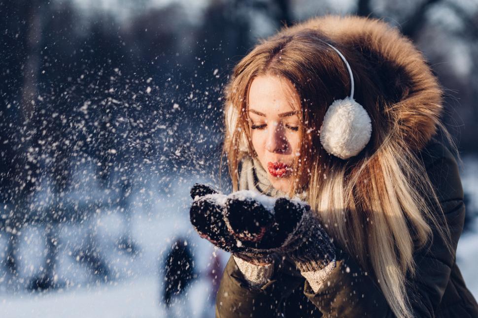 Free Image of Woman blowing snow from hands in winter 