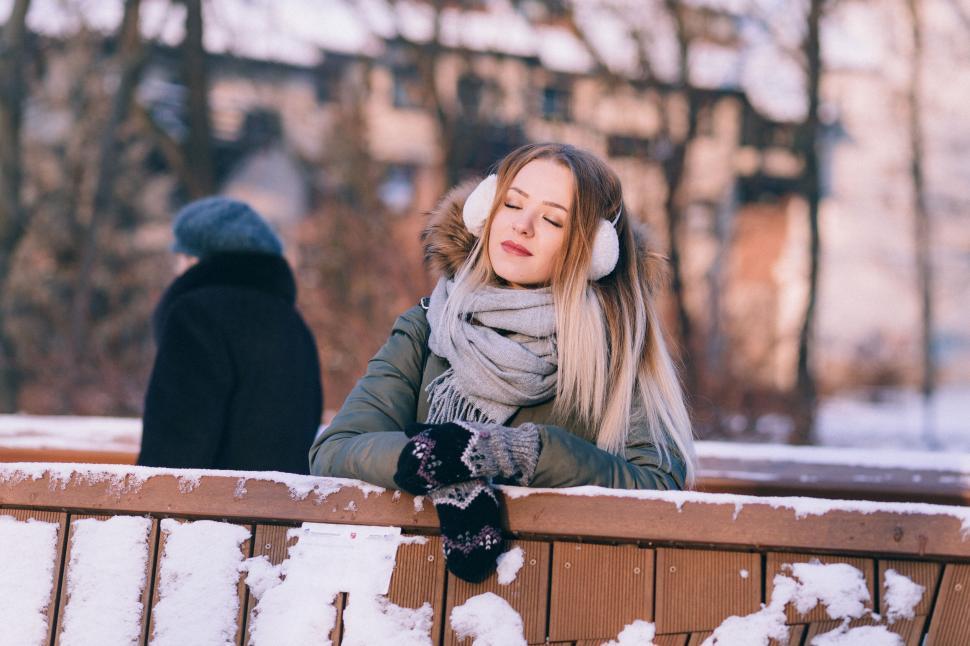 Free Image of Young woman resting on snowy park bench 