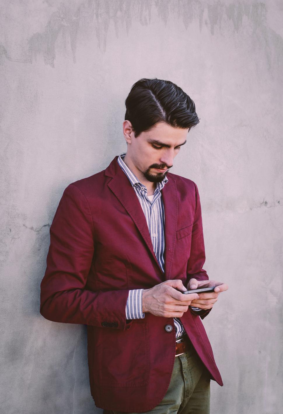 Free Image of Man in red jacket texting on phone 