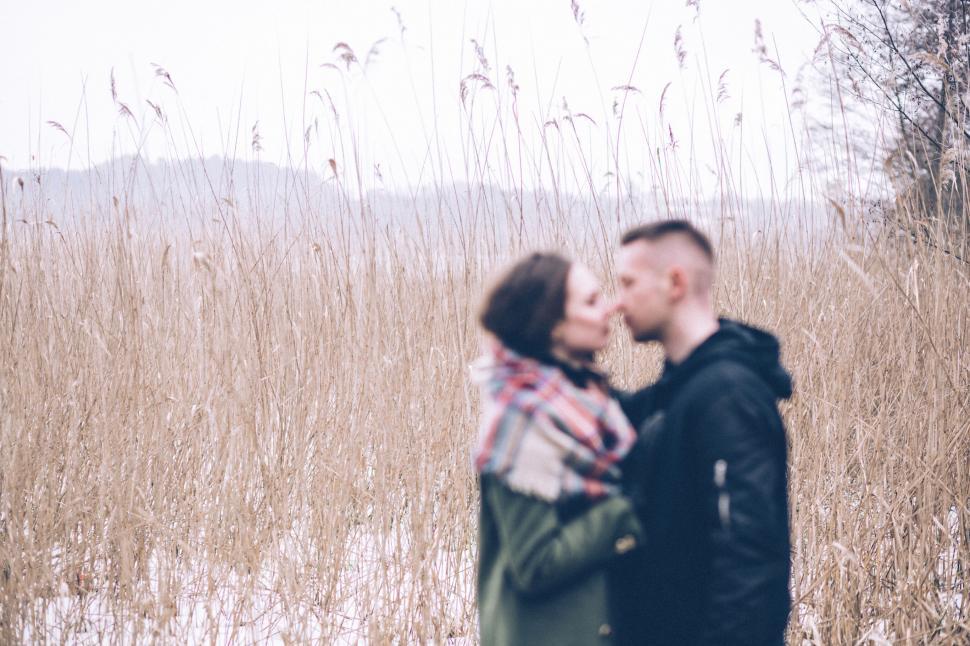 Free Image of Couple kissing in a reed field, face obscured 
