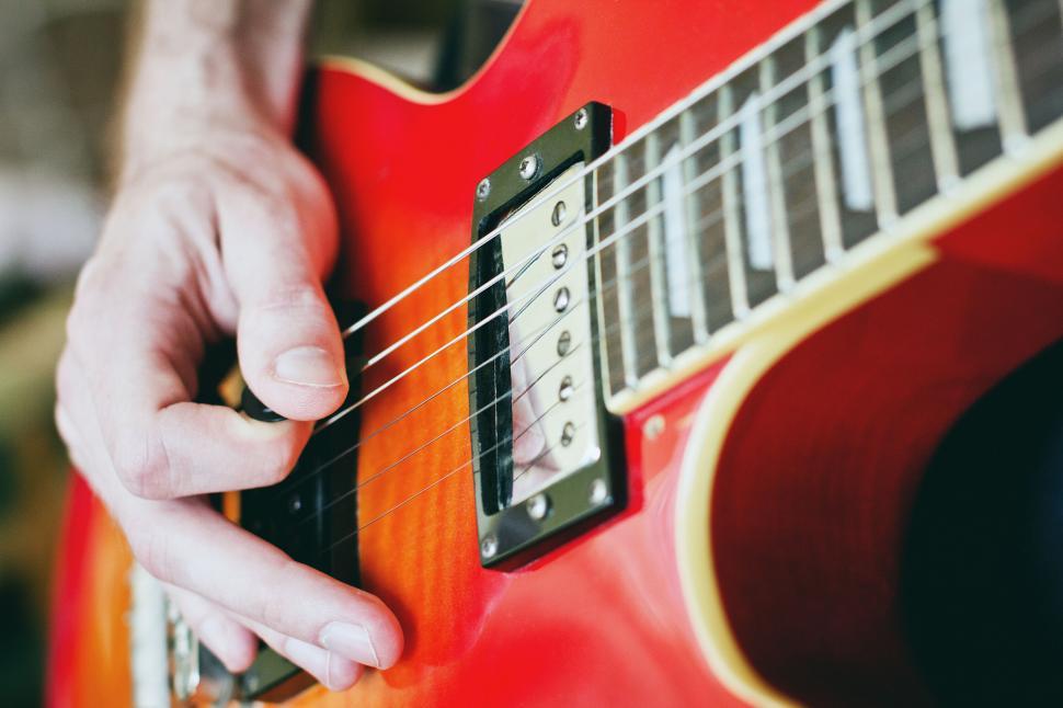 Free Image of Close-up of a hand playing red electric guitar 