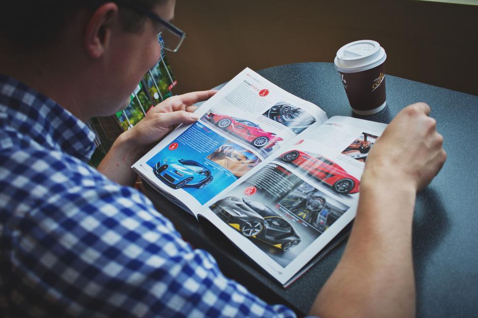 Free Image of Man reading a car magazine at a cafe 