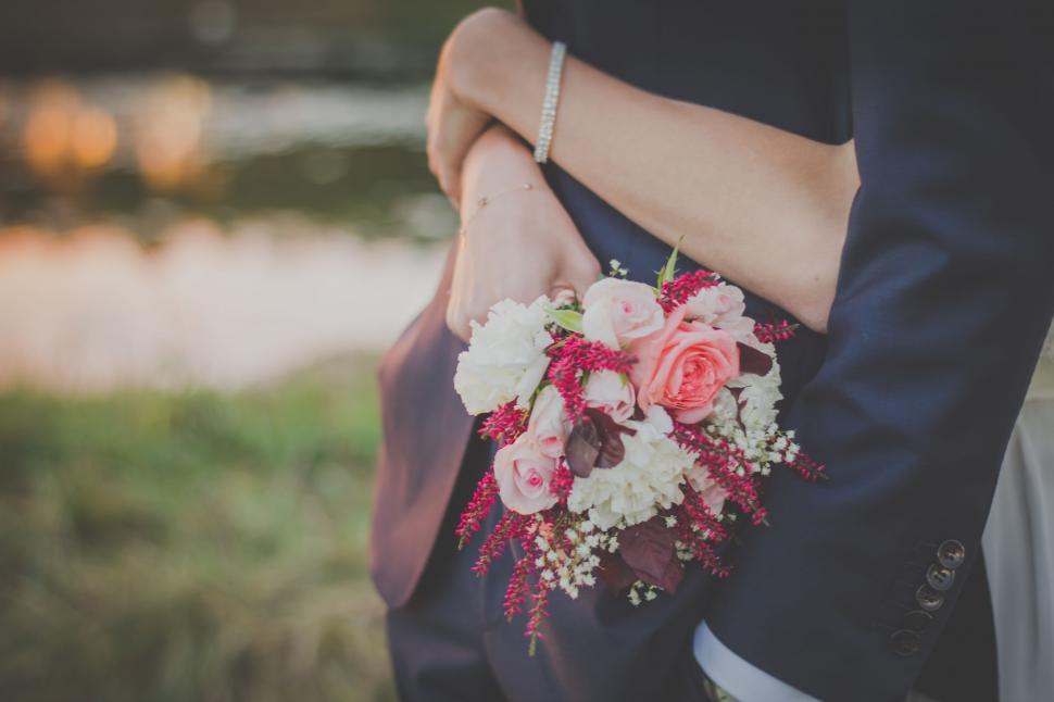 Free Image of Couple embracing with a wedding bouquet 