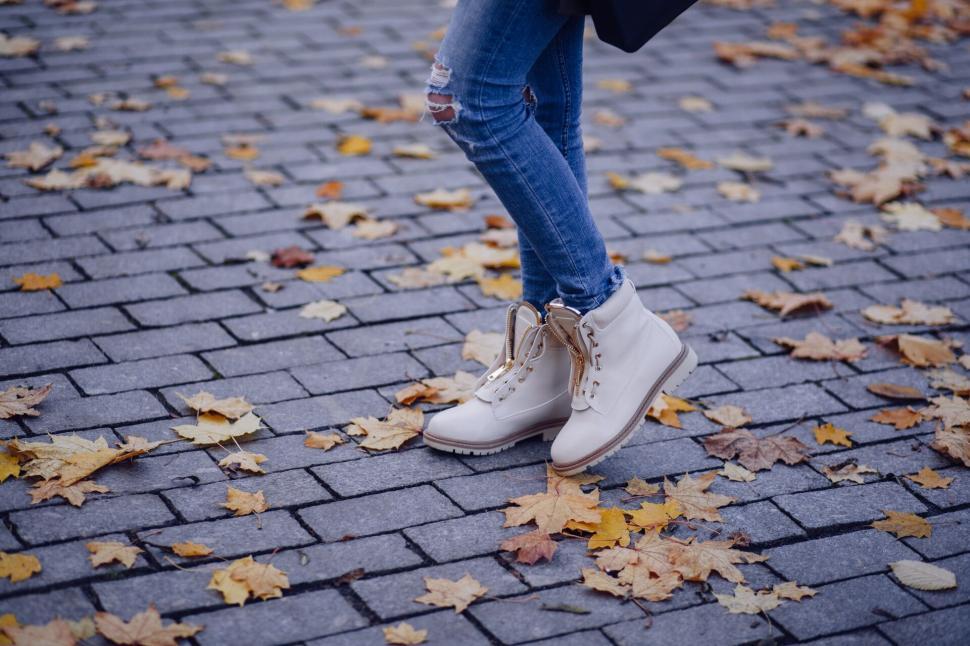 Free Image of Trendy woman s feet in white boots on cobblestone 