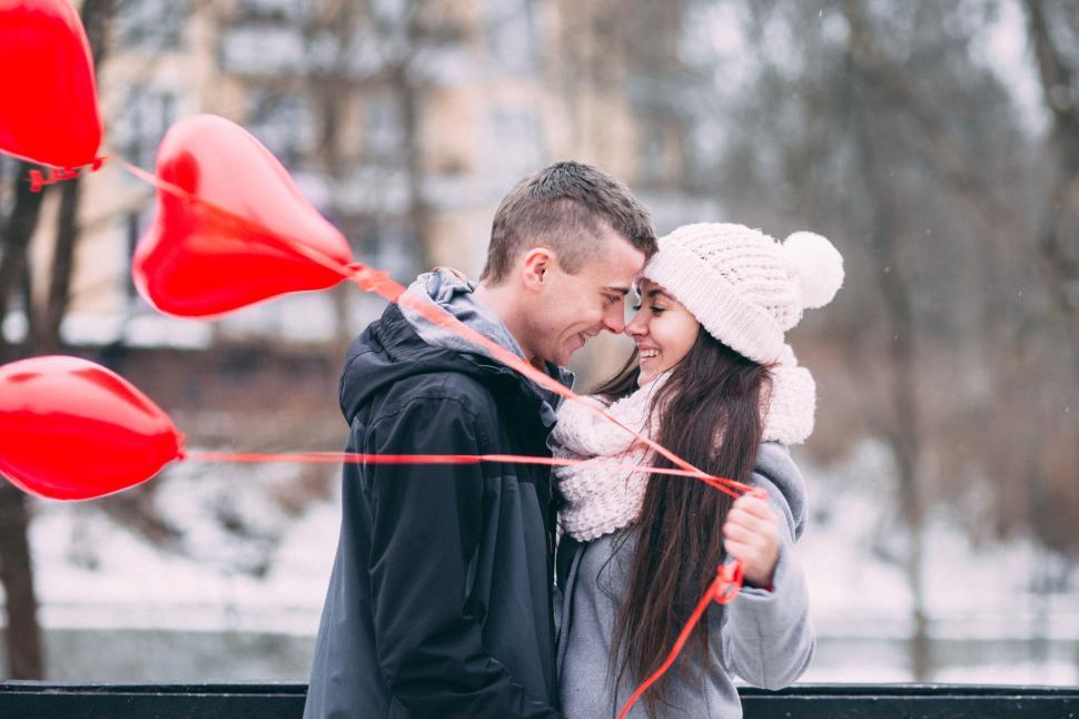 Free Image of Couple holding hands with heart-shaped balloons 