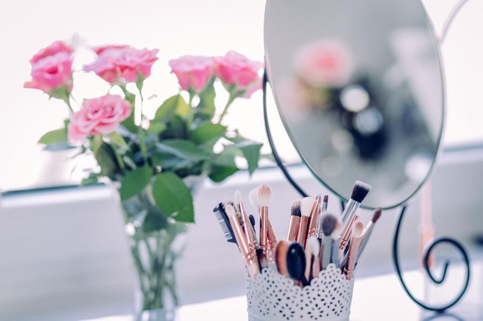 Free Image of Makeup brushes and roses reflected in mirror 