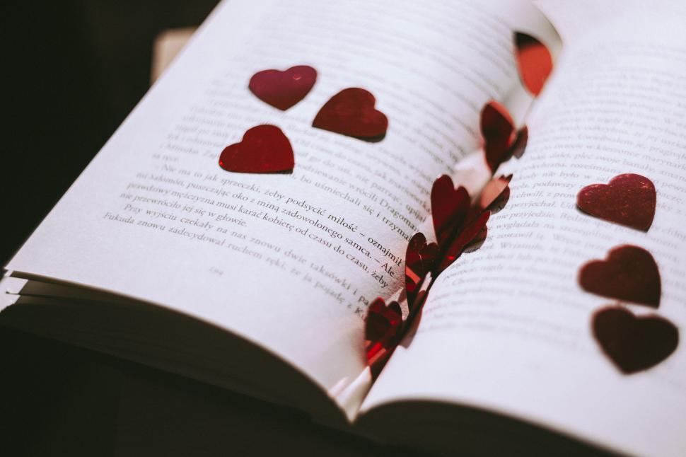 Free Image of Open book with heart shaped paper cutouts 
