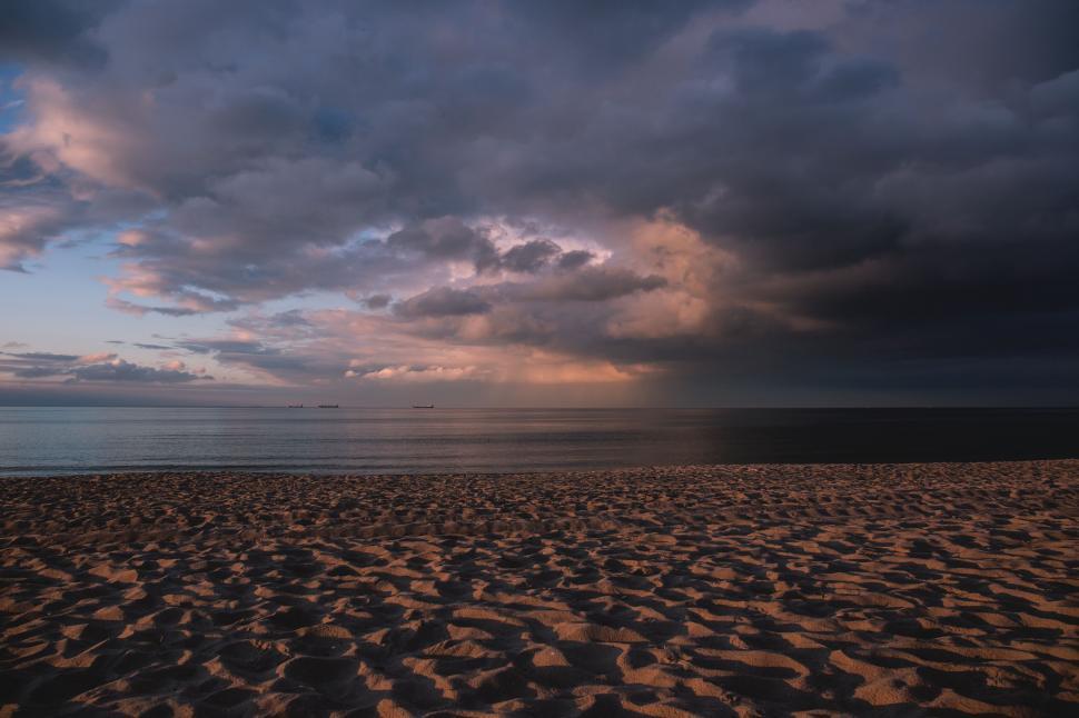 Free Image of Beach with dramatic sky during sunset 