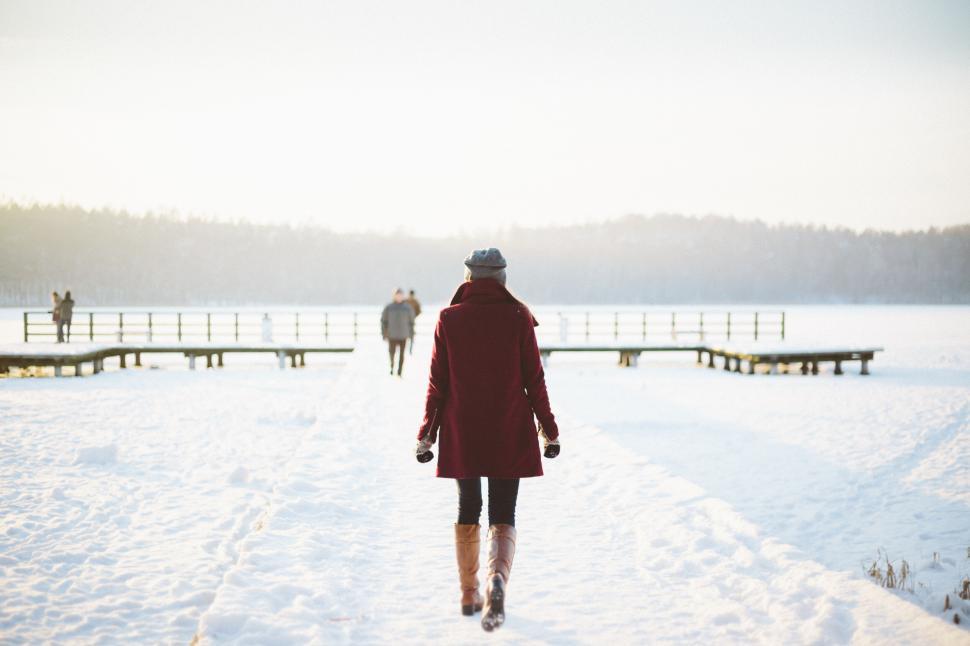 Free Image of Person walking on snowy dock by lake 
