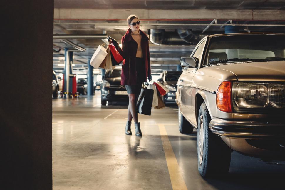 Free Image of Stylish woman walking in parking lot with bags 
