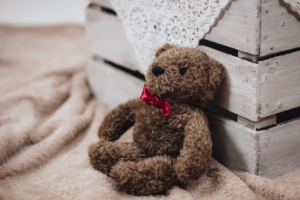 Free Image of Teddy Bear Sitting by a Wooden Crate 