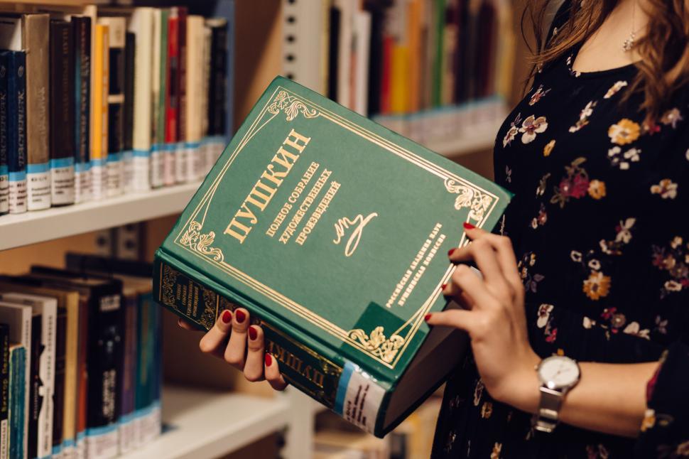 Free Image of Woman holding large vintage book in library 