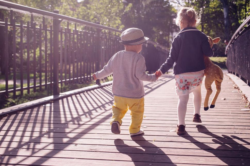 Free Image of Two children walking with a dog on a bridge 