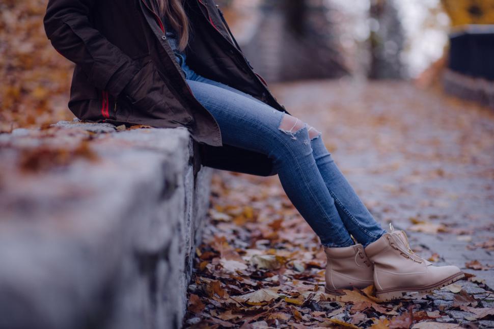 Free Image of Woman in jacket sitting on autumn leaves 